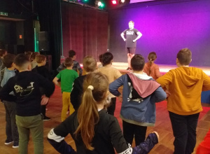 Uczniowie tańczą przed sceną w Centrum Kultury Młodych.